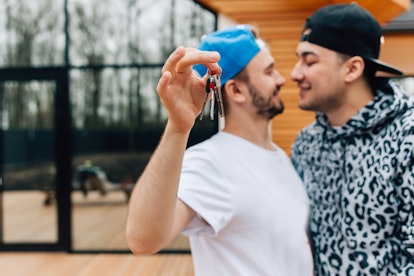 A man hugging with his friend and holding the keys of the house he bought