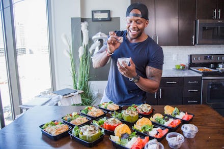 Kevin Curry standing next to a table with twelve food meals he prepared