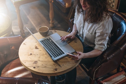 Unmarried women without kids happily drinking coffee and working on her laptop.