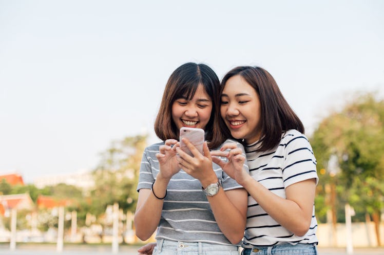 A pair of cousins looking at their phones deciding what cousin quotes to post on each other's Instag...