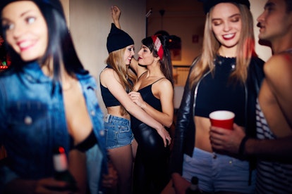 Two lesbian girls hugging and kissing at a party