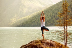 A woman doing yoga on a cliff with the view of a lake in the distance in Aspen
