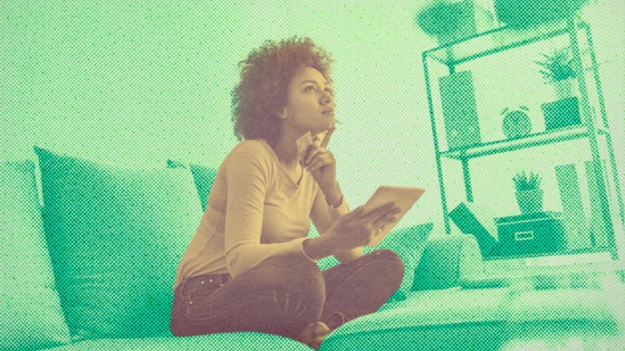A woman sitting on a couch and holding a notebook thinking about how to pay off her debt