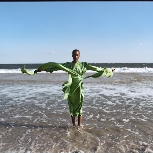 A model posing in a satin light-green Gucci dress on a beach 