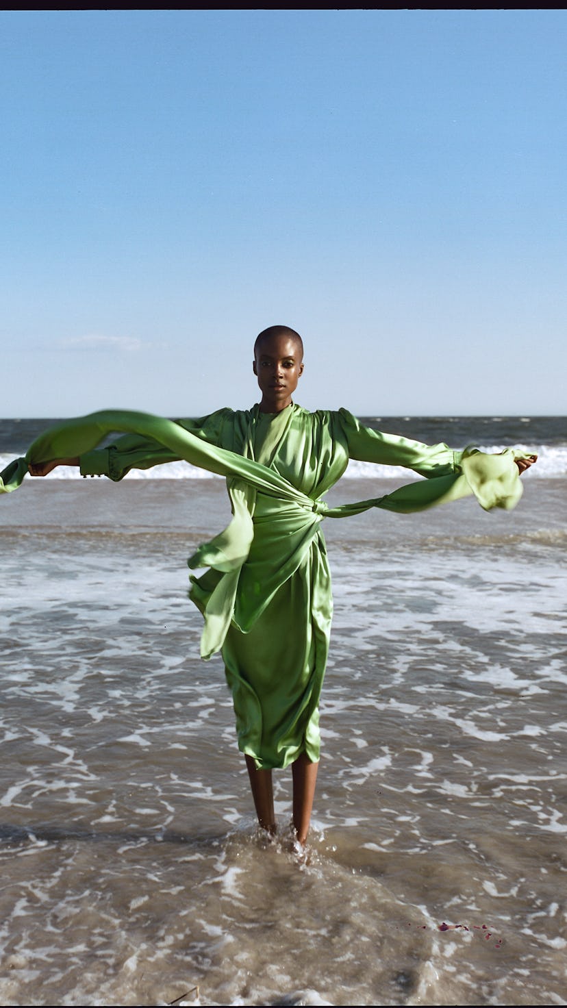 A model posing in a satin light-green Gucci dress on a beach 
