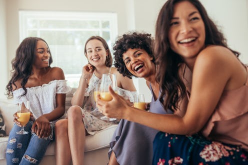 Four women at a rainbow baby shower, sitting and smiling while holding their drinks.