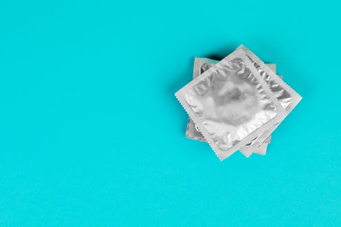 A stack of condoms in silver packaging on a blue background.