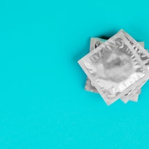 A stack of condoms in silver packaging on a blue background.