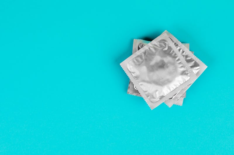 A stack of condoms in silver packaging on a blue background.