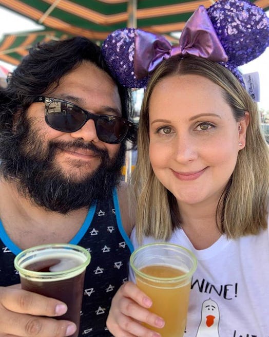 Kristen Cervantes with Minnie Mouse ears headband, posing while holding a beer next to her husband