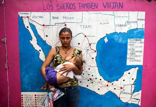 A mother breastfeeding her child in a public place next to a map on a wall