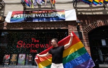 A man holding the LGBTQ+ flag on a street