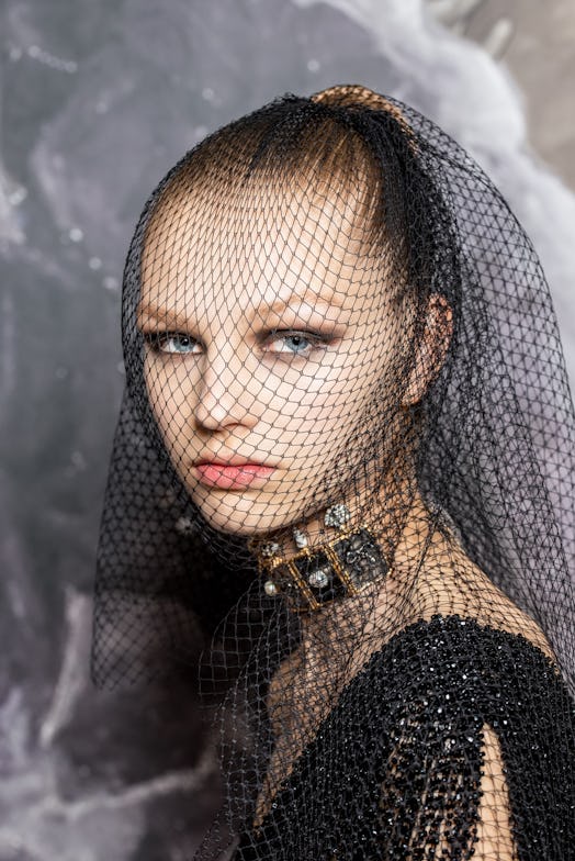 A model posing with a fishnet veil and Dior Haute Couture Fall/Winter 2019's Makeup Look 