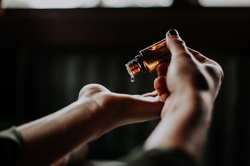 a pair of hands in front of a black background applying a skin serum