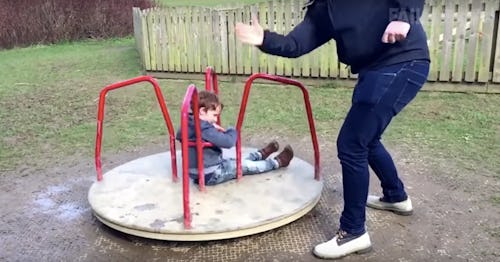 A dad spinning his child on a park spinner 