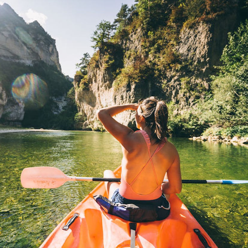Young woman paddling on the water before posting a pic on Instagram with kayaking quotes, kayak puns...