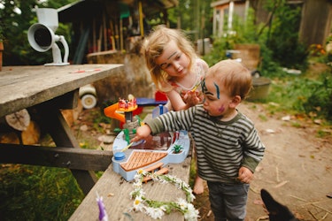 A 4-year-old Birdie painting her brother's face while playing outside