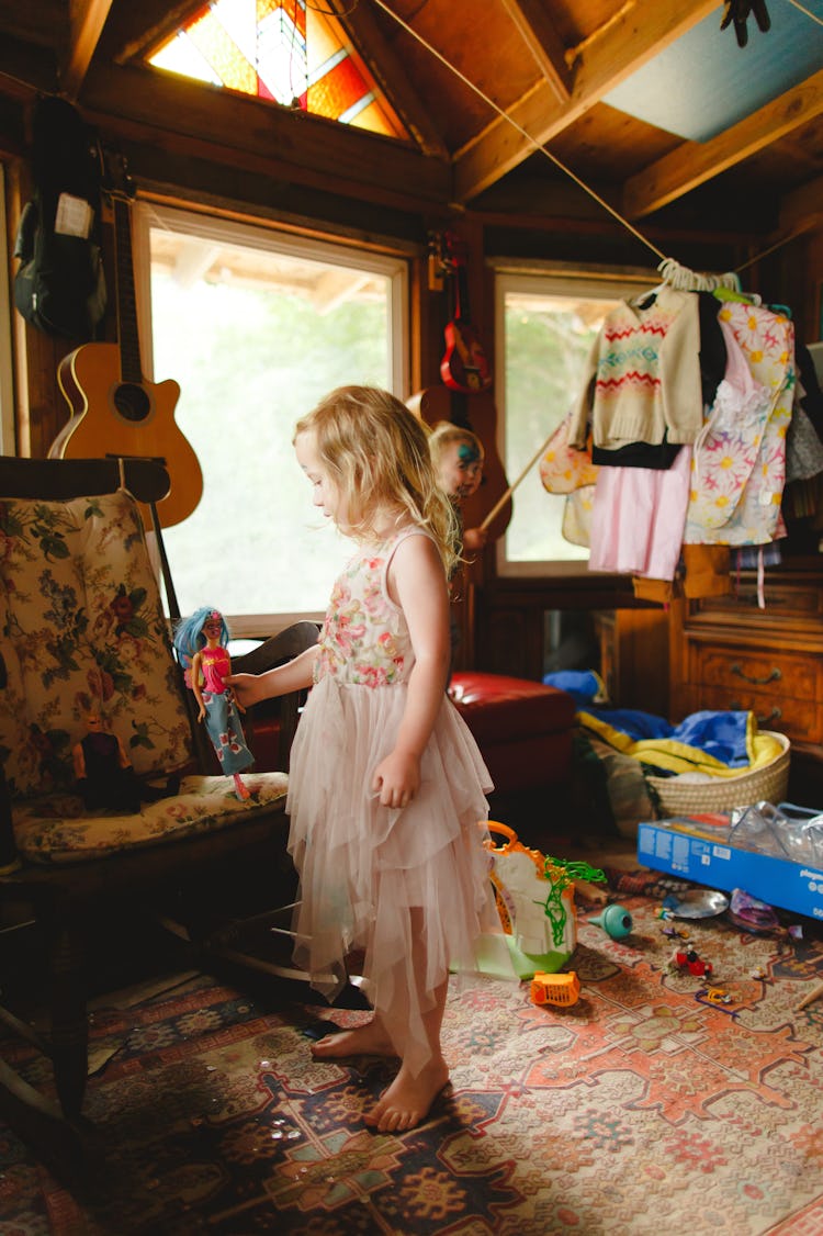 Birdie wearing a pink tulle dress while holding her barbie doll 