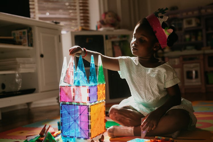 A 4-year-old Sloane, wearing a crown while building a colorful castle