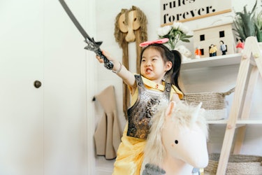 A 3-year-old Joey dressed as a warrior sitting on her white plush unicorn while holding her sword in...