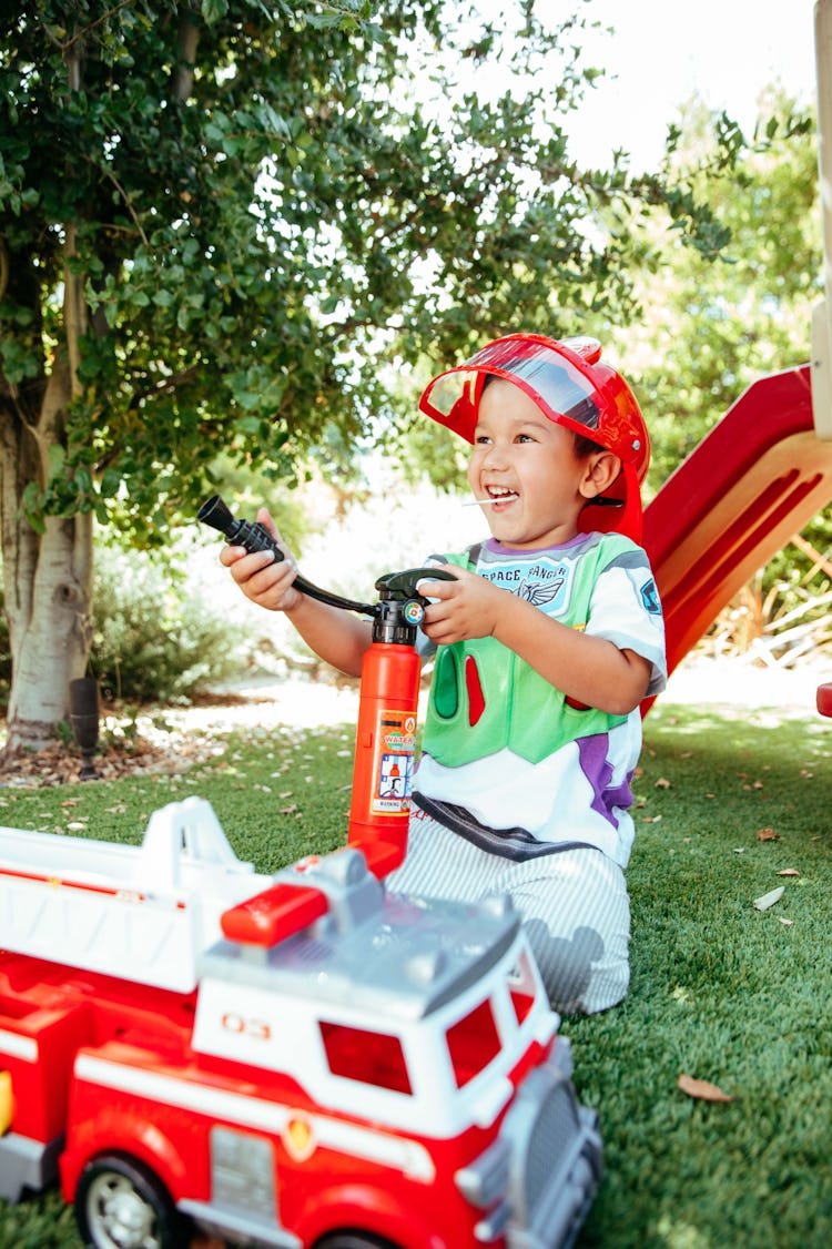 Ferris dressed as a firefighter holding a plastic fire extinguisher while playing outside. 