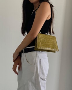 A young lady wearing a light green leather bag