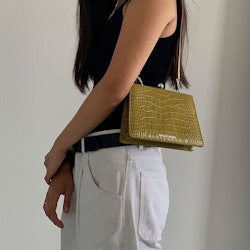 A young lady wearing a light green leather bag