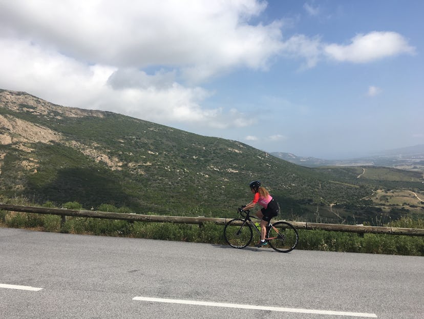 A bicyclist at the side of the road, looking off into the distance admiring the landscape