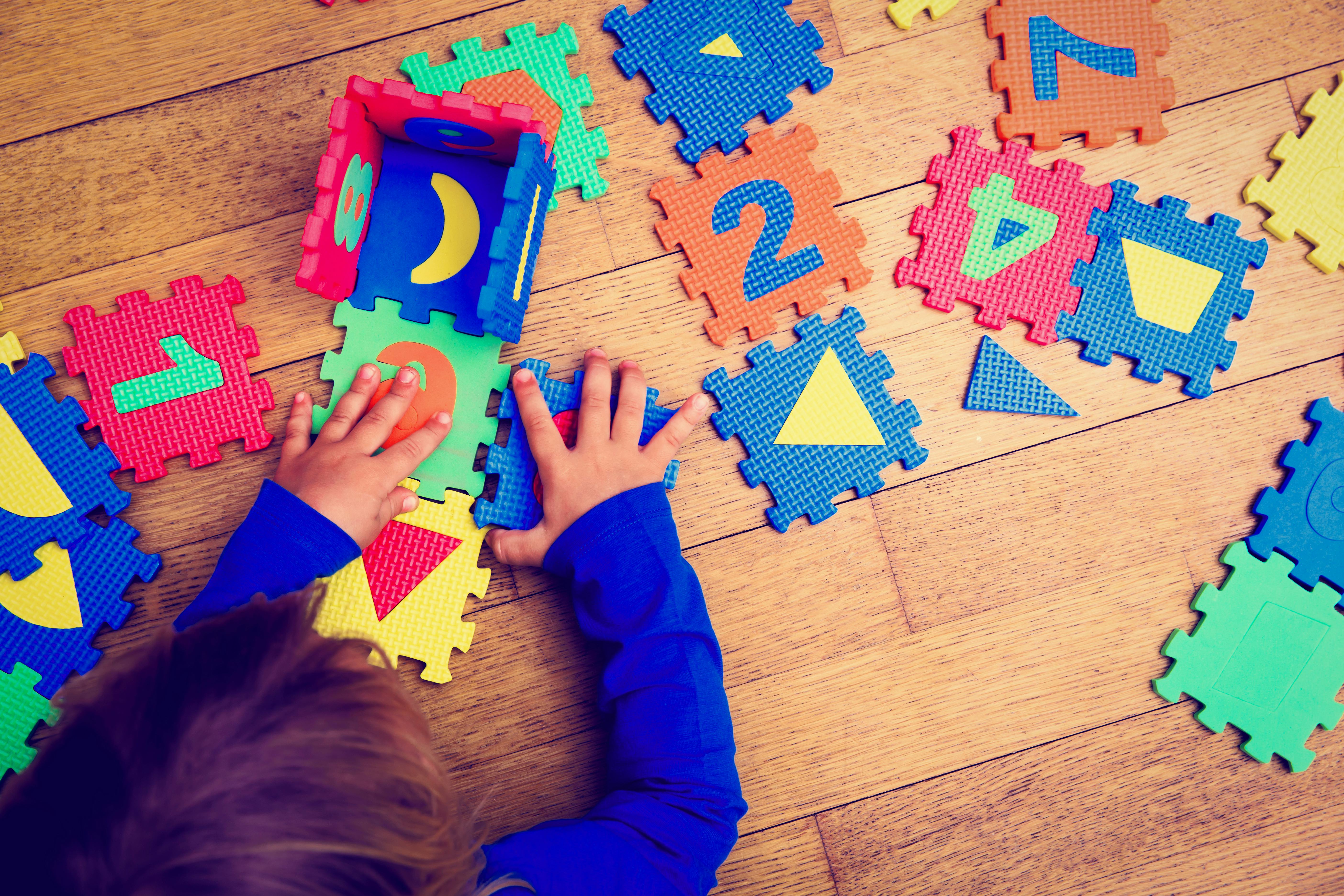 A child with autism assembling a number puzzle mat on the floor