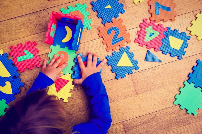 A child with autism assembling a number puzzle mat on the floor