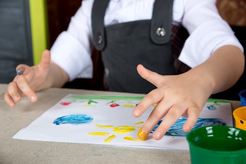 A child with autism painting a sun with its fingers and water colors 