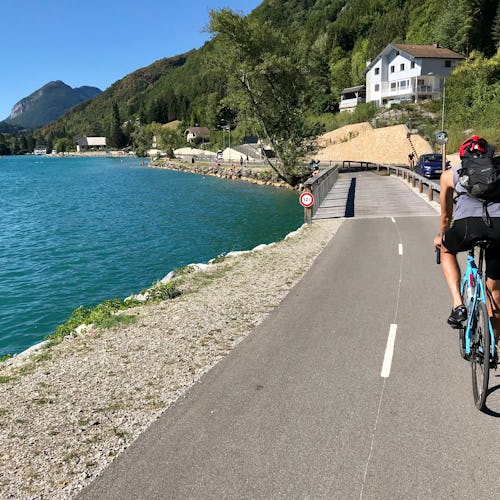 A person on a bicycle ride nest to a body of water on a bike lane next to the road