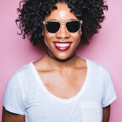 A curly haired girl smiling while wearing sunglasses