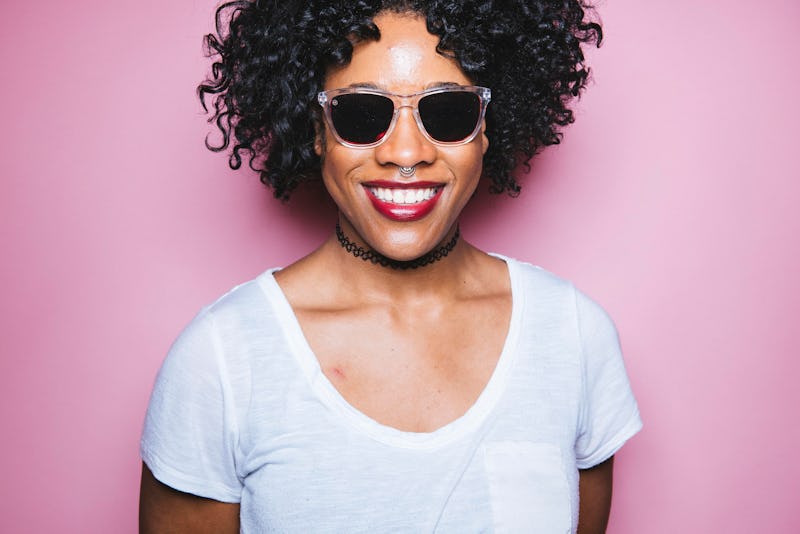 A curly haired girl smiling while wearing sunglasses