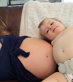 Toddler showing affection to pregnant mom by touching bellies