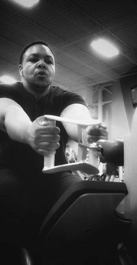 An overweight black man does weight exercises in the gym. 
