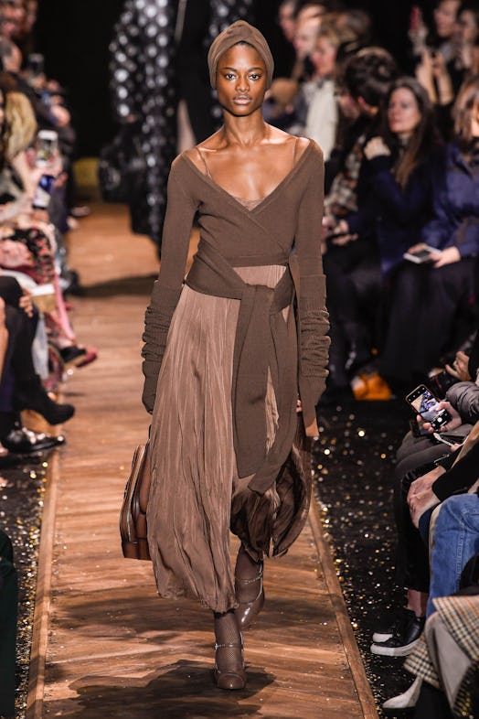 A model on a runway in a brown top and beige sating skirt