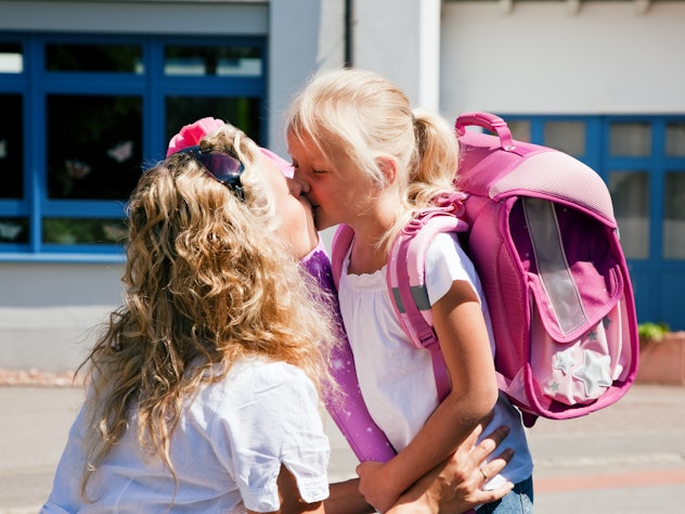 A mom kissing her daughter goodbye at school drop off 