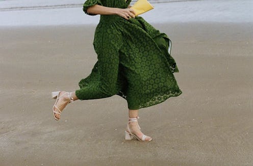 A girl in a green dress walking in white leather sandals