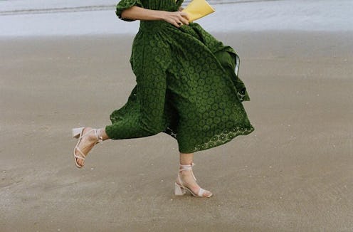 A girl in a green dress walking in white leather sandals