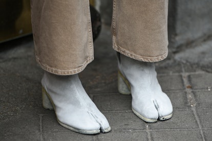 A woman standing while wearing white square-toe leather heels