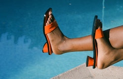 A woman sitting next to a pool in square-toe heel sandals 