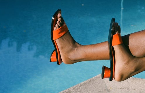 A woman sitting next to a pool in square-toe heel sandals