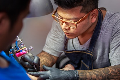 A tattoo master tattooing a man