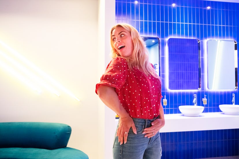 Busy Philipps in a red polka-dot blouse and high-waisted jeans posing with her arm on her waist 