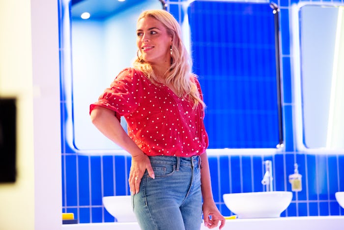 Busy Philipps in a red polka-dot blouse and high-waisted jeans posing in a bathroom
