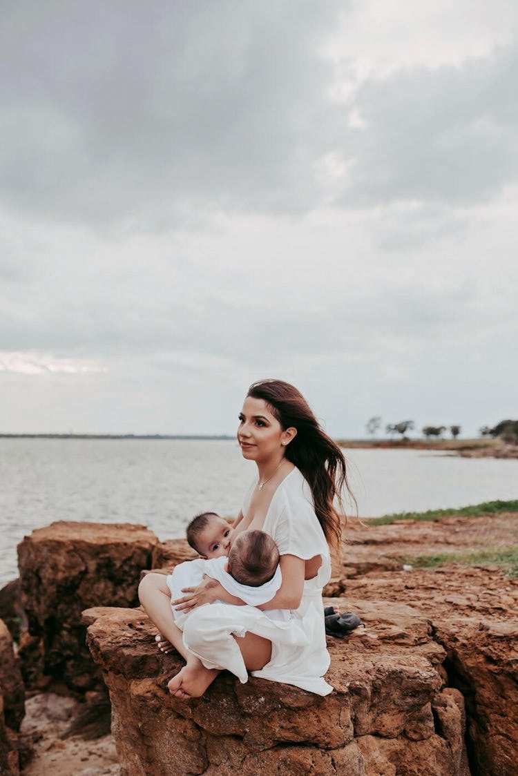 mom breastfeeding twins by the sea