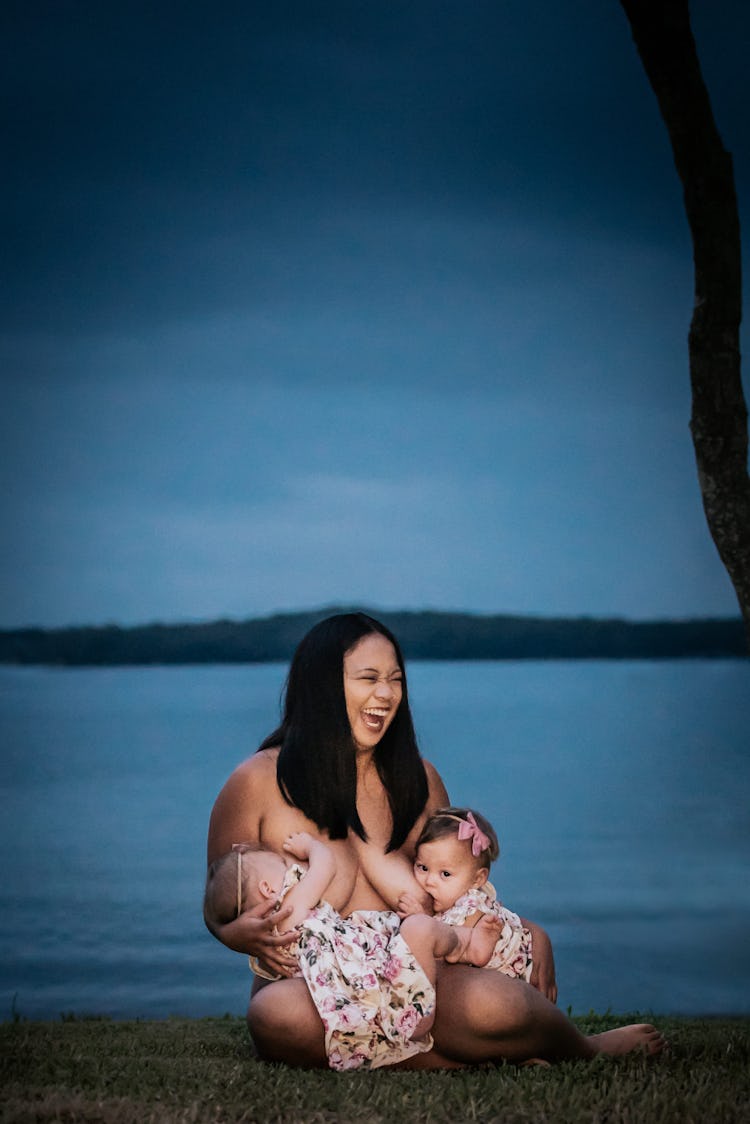 mom tandem breastfeeding children on the beach at night