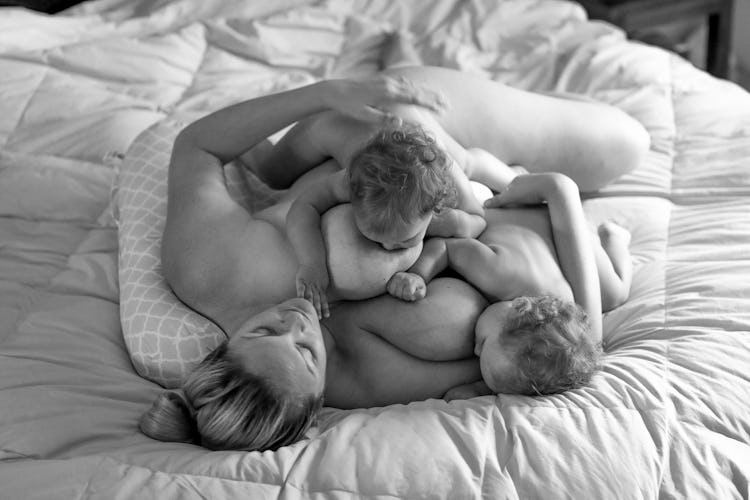 mom lying in bed, tandem breastfeeding twins