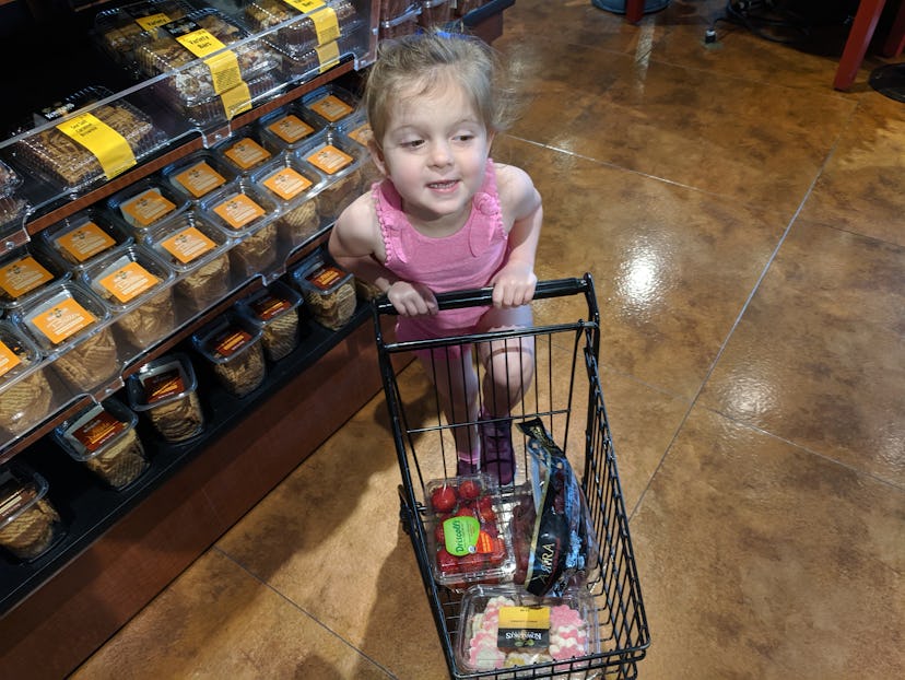 Lisa Kerslake's toddler in a supermarket with a tiny black shopping cart with items in it